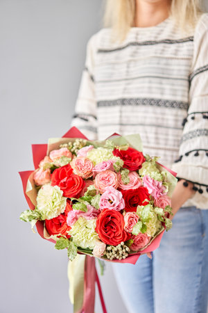 Small Beautiful bouquets of mixed flowers in woman hand. Floral shop concept . Beautiful fresh cut bouquet. Flowers deliveryの写真素材