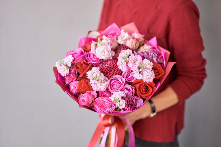 Two Small Beautiful bouquets of mixed flowers in woman hand. Floral shop concept . Beautiful fresh cut bouquet. Flowers deliveryの写真素材