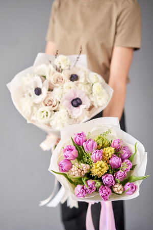 Two Small Beautiful bouquets of mixed flowers in woman hand. Floral shop concept . Beautiful fresh cut bouquet. Flowers deliveryの写真素材