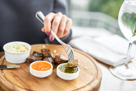 Lunch in a restaurant, a woman eats Pieces of liver cooked on the grill. Serving on a wooden Board. Barbecue restaurant menu, a series of photos of different meats.の写真素材