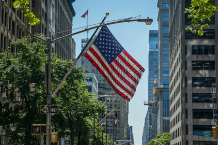 US flag flying in city street amidst towering buildingsの素材