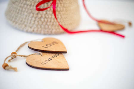 Wooden valentines with the inscription love on a white solid background. Handmade wicker basket in the backgroundの写真素材