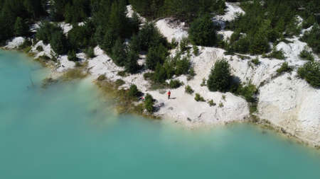 A girl in a dress floats on a glanders board on a pond with bright turquoise water. Warm summer day...