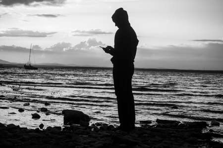 Mountain lake at sunset. The yacht sways on the waves. Silhouette of a girl at sunsetの写真素材