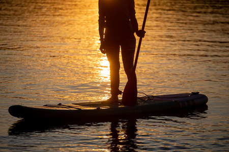 Girl on sup board with beautiful colored sunrise background mountains background