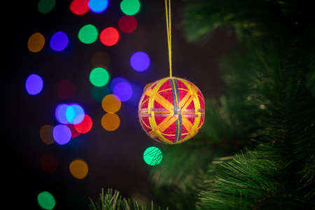 Christmas New Year's handmade toy hangs on a green spruce branch. Ball braided from threadsの写真素材