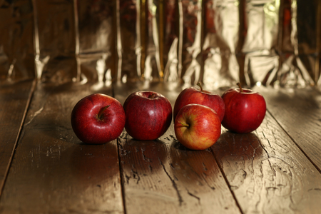 Red apples lie on an old wooden surfaceの写真素材