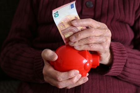 Retiree puts money into the piggy bank