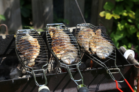 Fish grill on the grill and grilled. Fresh raw fish on the grill. Cooked in traditional style. Cooking salted fish on a barbecue stove.の写真素材
