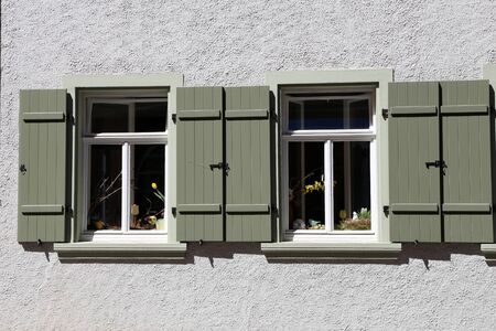 The windows of the house with shutters and flowersの写真素材