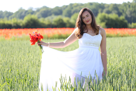 Portrait of a girl with poppies in wheat field.の写真素材