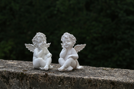Two miniature angels on a stone wallの写真素材