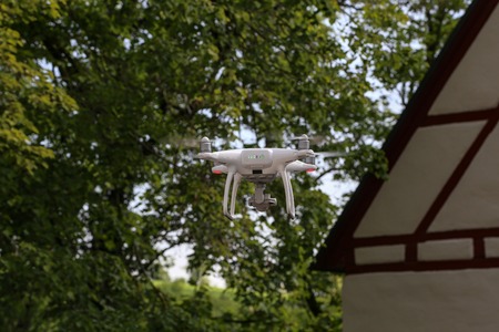 Flying quadcopter with digital camera on blurred background.