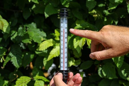 Hot Summer - Thermometer in hand, shows the heat.の写真素材