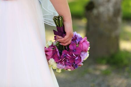 The bride holds a wedding bouquet in her hand against the background of a white dress.の写真素材