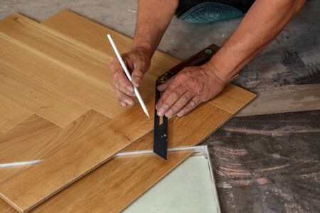 Worker laying parquet flooring. Worker installing wooden laminate flooring.