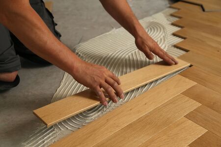 Worker laying parquet flooring. Worker installing wooden laminate flooring.の写真素材