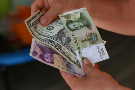 Dollar vs Yuan. Dollars and yuan in the hands.の写真素材