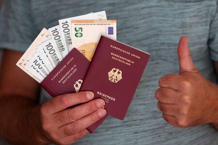 Two new German passports and vacation money in the hands of a manの写真素材