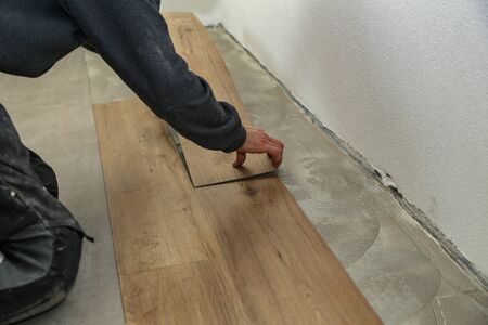 The worker installing new vinyl tile floor.の写真素材