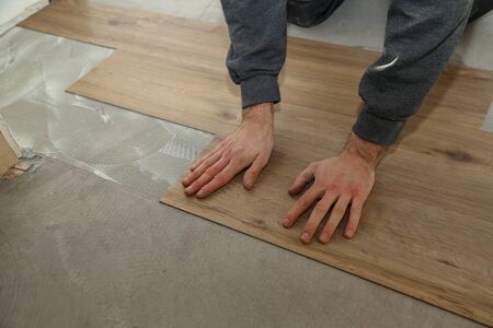 The worker installing new vinyl tile floor.の写真素材