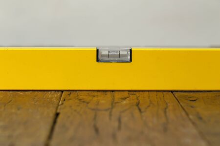 Yellow building level lies on a wooden table.
