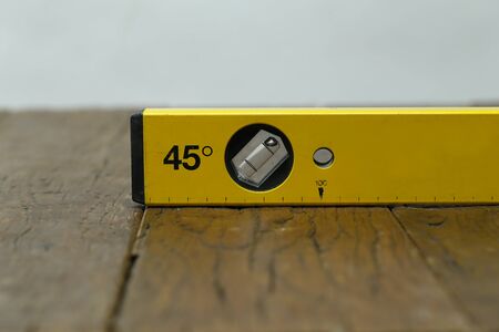 Yellow building level lies on a wooden table.
