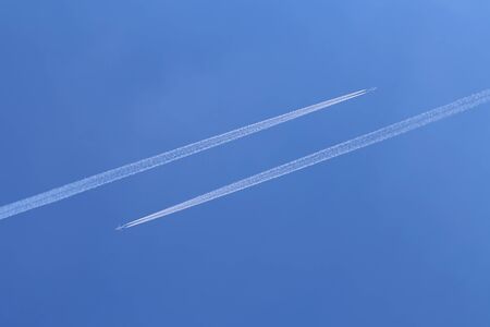 Trails from airplanes in the blue sky.の写真素材
