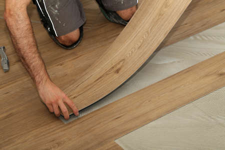 The worker installing new vinyl tile floor.