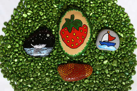 Beautifully painted stones lie on green stones.の写真素材