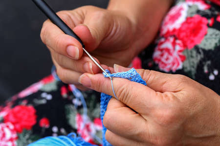 Hands of a needlewoman crochet. Female fingers knit a toy. Handmade craft.
