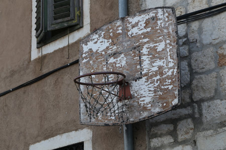 An old basketball ring is attached to the wall of the house.の写真素材