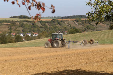 Tractor at agricultural work in the field in autumnの写真素材