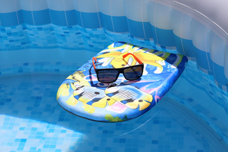 Swimming board with sunglasses in the pool.
