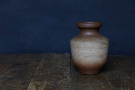 Beautiful clay vase stands on the wooden floor.