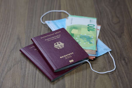 Passport with money and mouth and nose protection mask - traveling during the corona pandemicの写真素材