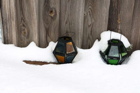Colored glass lanterns stand outside in the snow.の写真素材