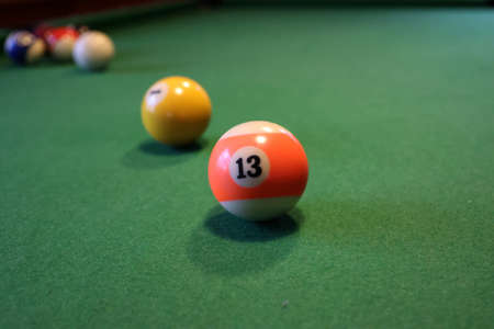 Colored pool balls on a green pool table. Billiard ball with number thirteen.の写真素材