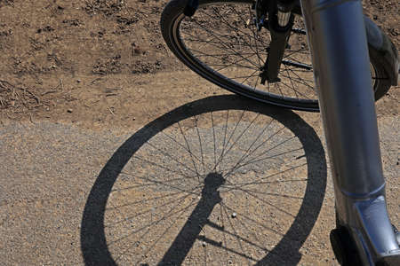 Bicycle wheel and its shadow on the asphalt.