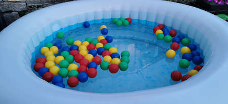 Multicolored balls float in the bubbling water of an inflatable poolの写真素材