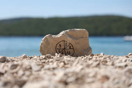 Stone with pictogram from numbers on the beach.