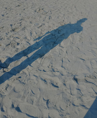 Shadows cast on golden sand under bright sunlightの写真素材