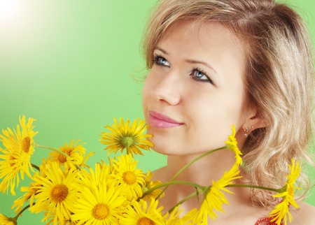 Beautiful blond with the yellow flowers against the green backgroundの写真素材