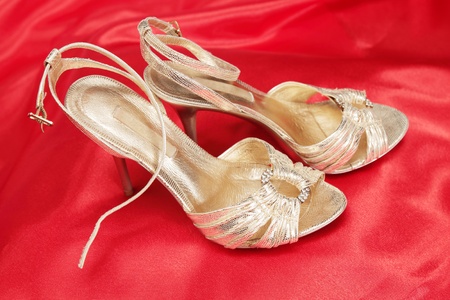 Golden sandals on the high heel on the red clothの写真素材