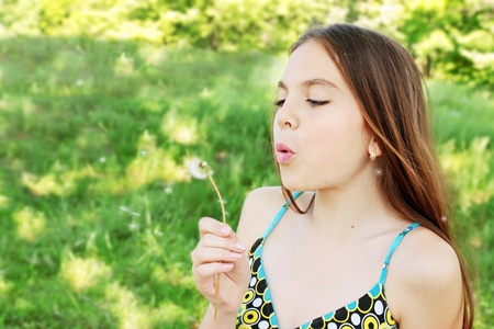 Young beautiful girl blowing  to the dandelionの写真素材