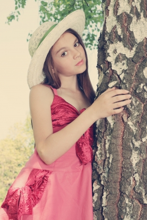 Dreamy girl in a hat standing near a birchの写真素材