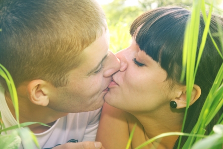 Couple kissing while lying in the grassの写真素材