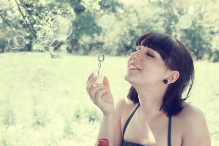 Young woman blow bubbles in the meadowの写真素材