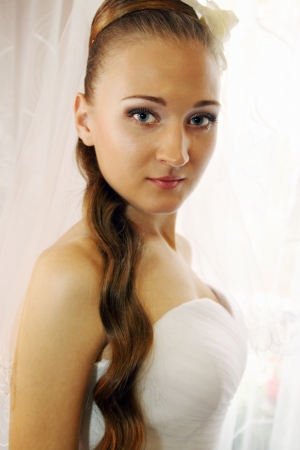 Portrait of a beautiful bride standing at the windowの写真素材