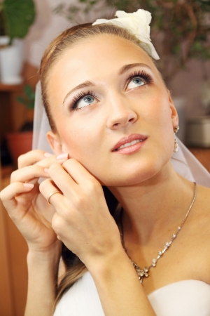 Young beautiful bride in necklace wears earringsの写真素材